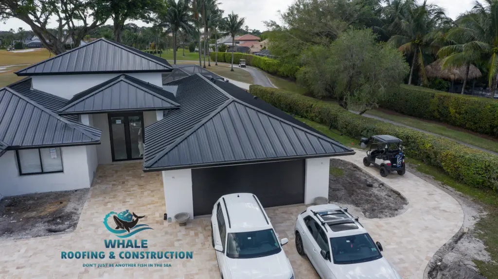Metal Roof Replacement in Parkland 4 A modern house with a dark metal roof, white exterior, two white vehicles parked in the driveway, and a golf cart nearby. Whale Roofing & Construction logo is visible.