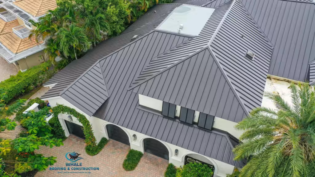 Roofing Trends That South Florida Homeowners Can't Ignore in 2025 2 Aerial view of a house with a dark gray metal roof, light-colored exterior walls, arched garage doors, and surrounding green landscaping.