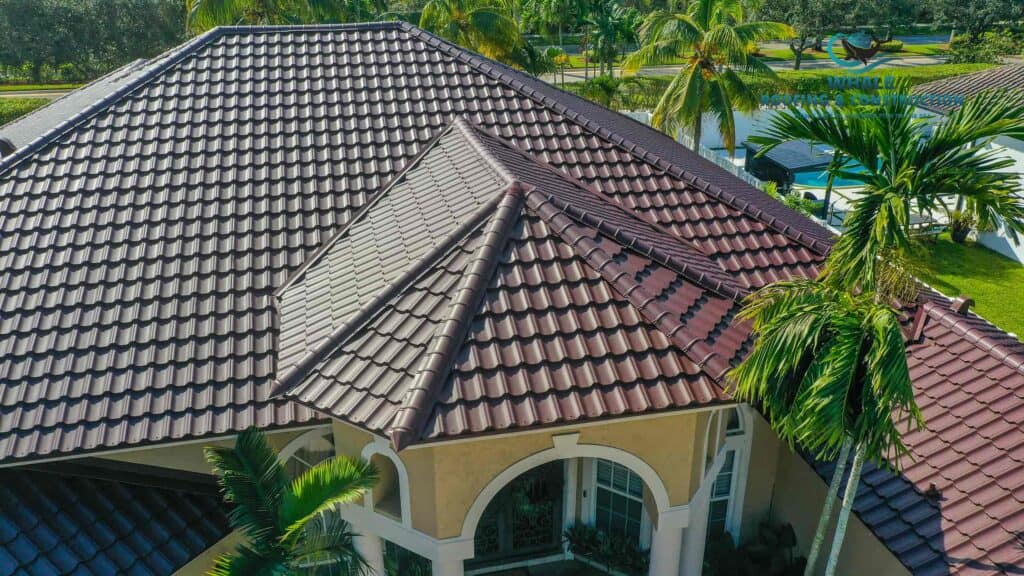 How To Conduct A Roof Inspection For Storm Damage: A Homeowner's Safety Guide 2 Aerial view of a house with a brown tile roof, arched windows, and tropical landscaping including palm trees.