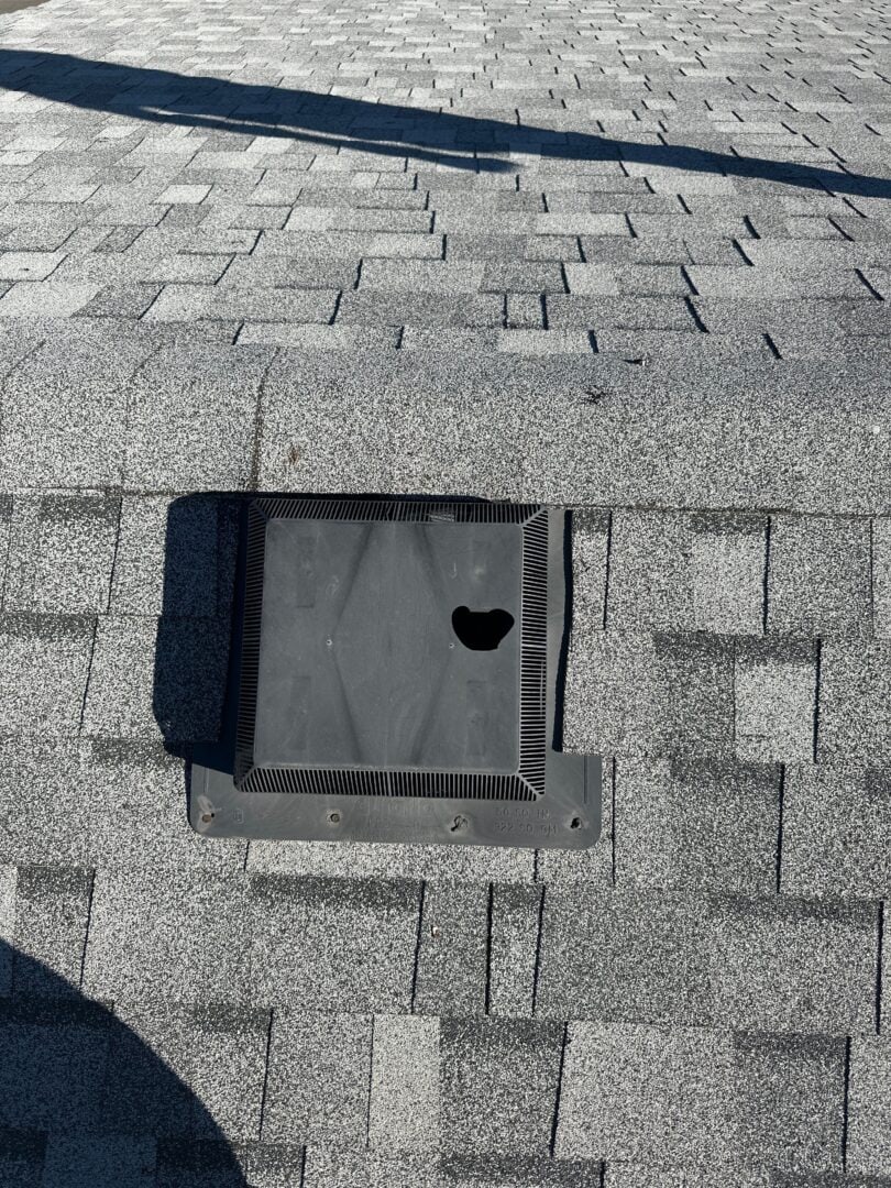 Hail-damaged roof vent on asphalt shingle roof in Calgary with visible puncture from storm impact