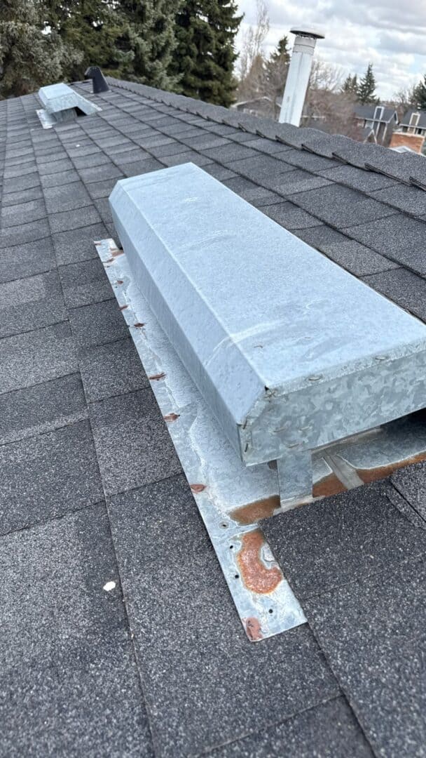 Close-up of an aging roof vent on an asphalt shingle roof in Calgary, showing rust and poor sealing—an example of how neglected roof components can undermine a new roofing project.