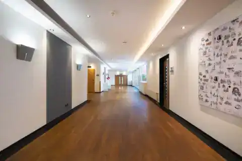 CongressCentrum Foyer – Fluchtperspektive. Langer Flur, Hannover-Motivwand rechts, Terrassentüren und Fenster rechts, Holzboden, Deckenbeleuchtung