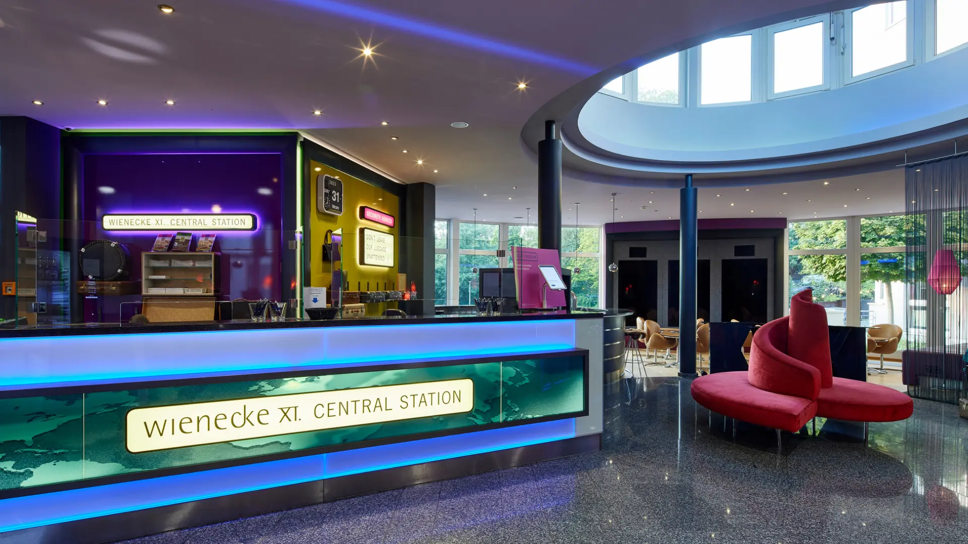 Moderne Hotellobby mit farbiger Rezeption, Designer-Loungemöbeln und ovalem Tageslichtfenster