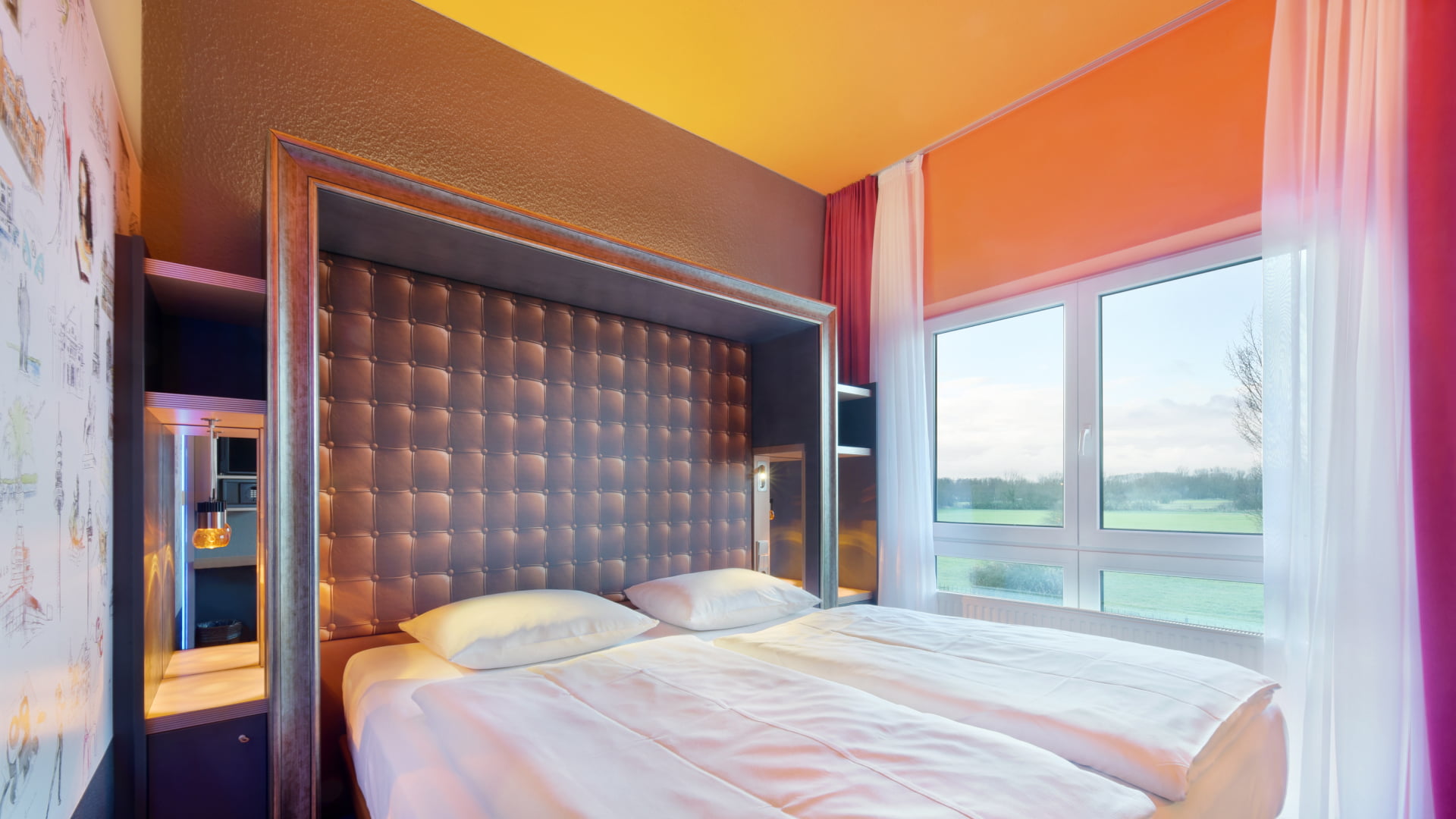 Hotelzimmer-Ansicht mit Blick auf das Bett und Fenster dahinter, mit offenen Vorhängen und Blick in das Landschaftsschutzgebiet.