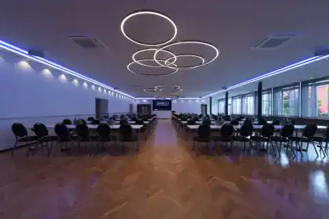 Kleiner Saal mit parlamentarischer Bestuhlung. Variable LED-Beleuchtung für verschiedene Veranstaltungstypen. Hier: Blau