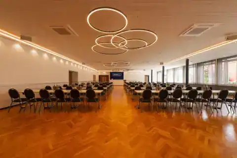 Kleiner Saal mit parlamentarischer Bestuhlung. Variable LED-Beleuchtung für verschiedene Veranstaltungstypen. Hier: Gelb