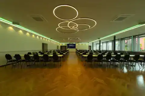 Kleiner Saal mit parlamentarischer Bestuhlung. Variable LED-Beleuchtung für verschiedene Veranstaltungstypen. Hier: Grün