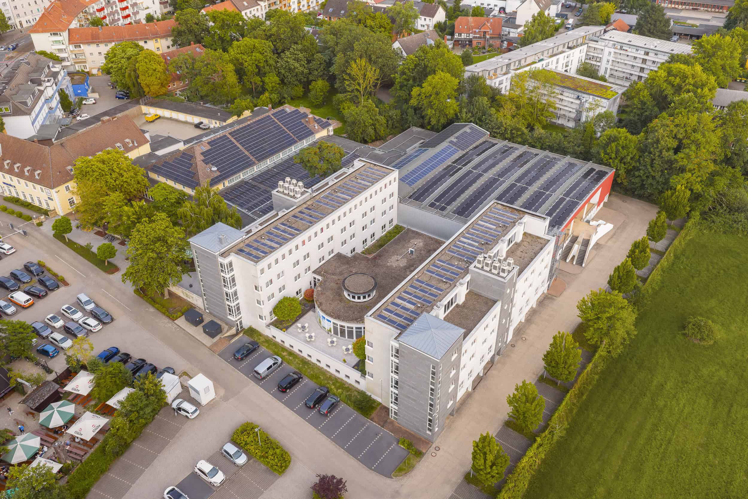 Vogelperspektive des Hotels mit Fotovoltaik-Anlagen, umgeben von angrenzendem Landschaftsschutzgebiet.
