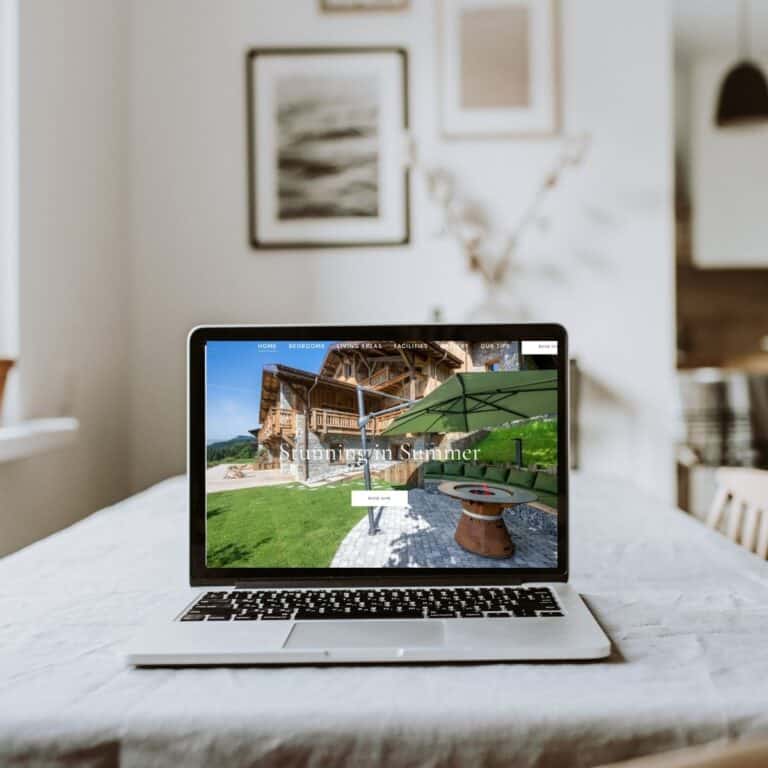 A laptop displaying a website with outdoor furniture and a green umbrella in a cozy indoor setting.