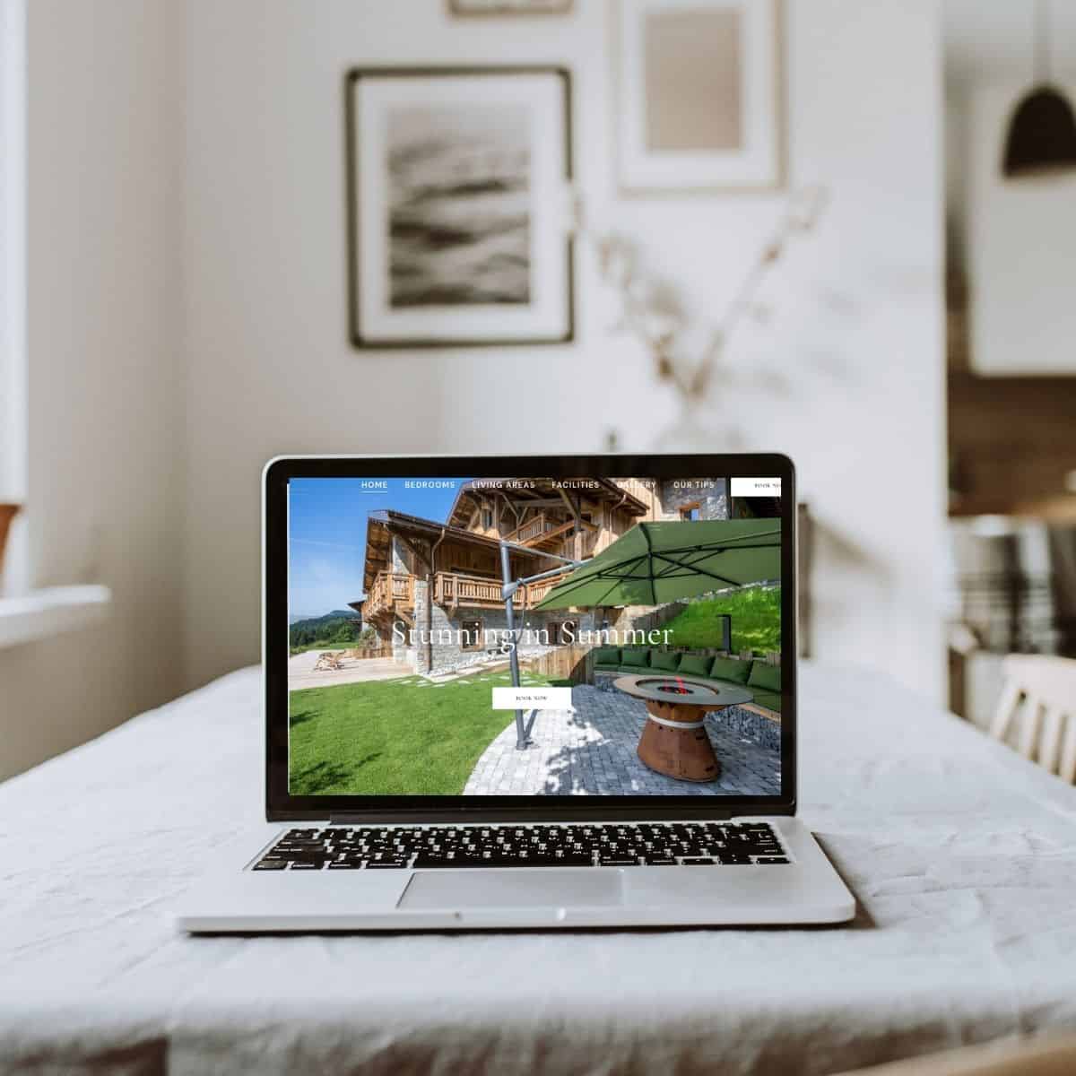 A laptop displaying a website with outdoor furniture and a green umbrella in a cozy indoor setting.