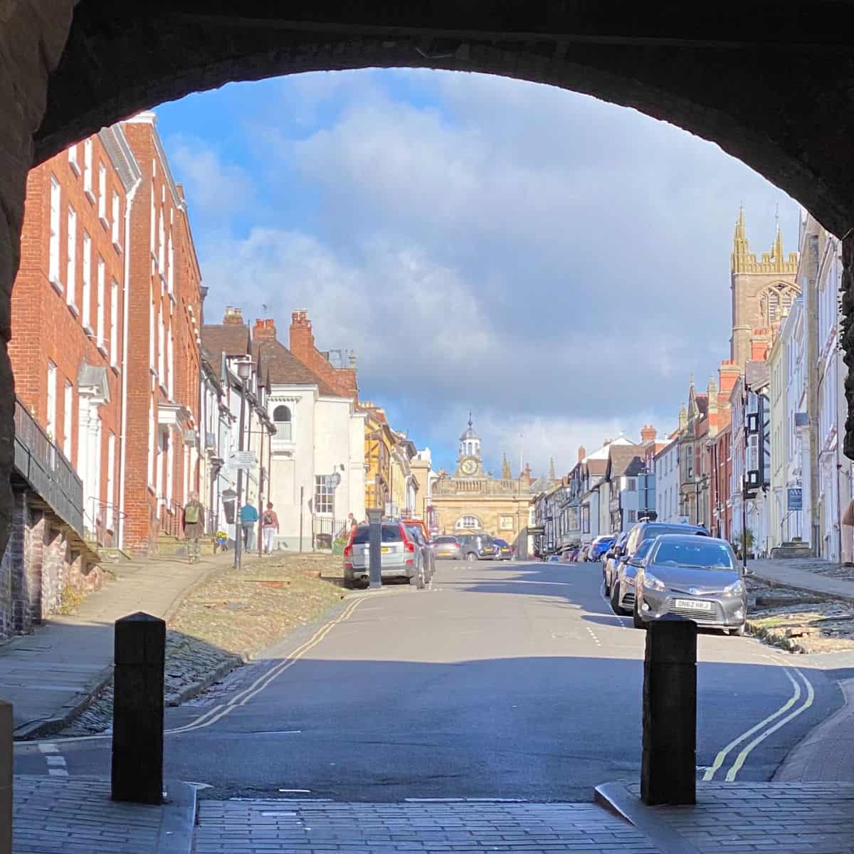 View of historic street with colorful buildings and church spire in the background.
