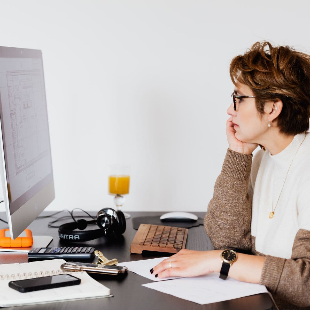 A woman working at a computer desk, asking questions about website design.