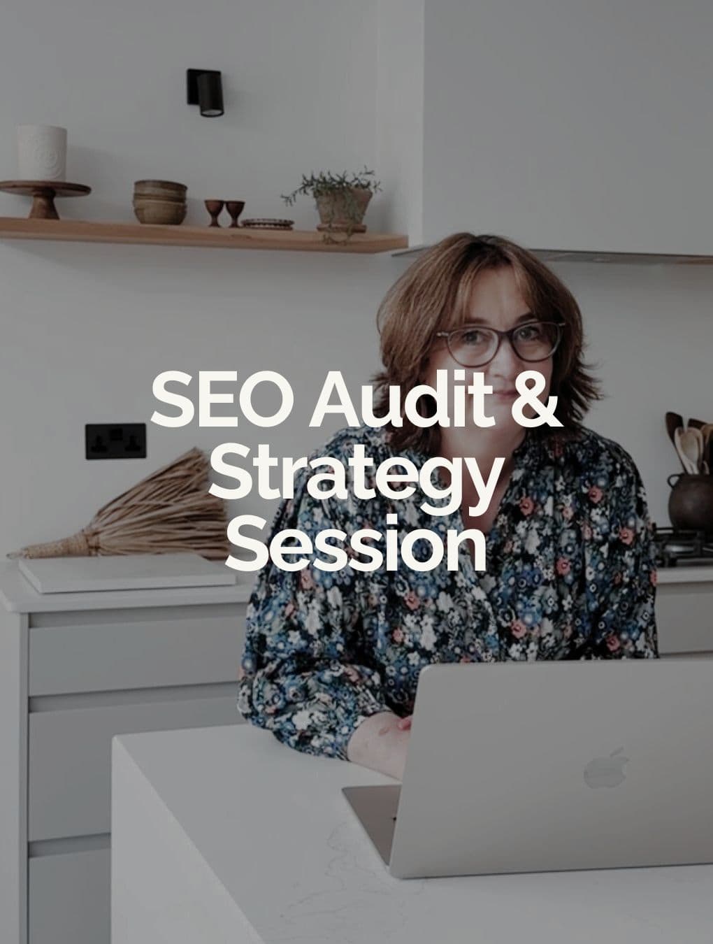A person with glasses sits at a kitchen counter using a laptop. The text SEO Audit & Strategy Session is overlaid on the image, highlighting Small Business SEO Services. Shelves with decor items are in the background. Wildcurrant Marketing
