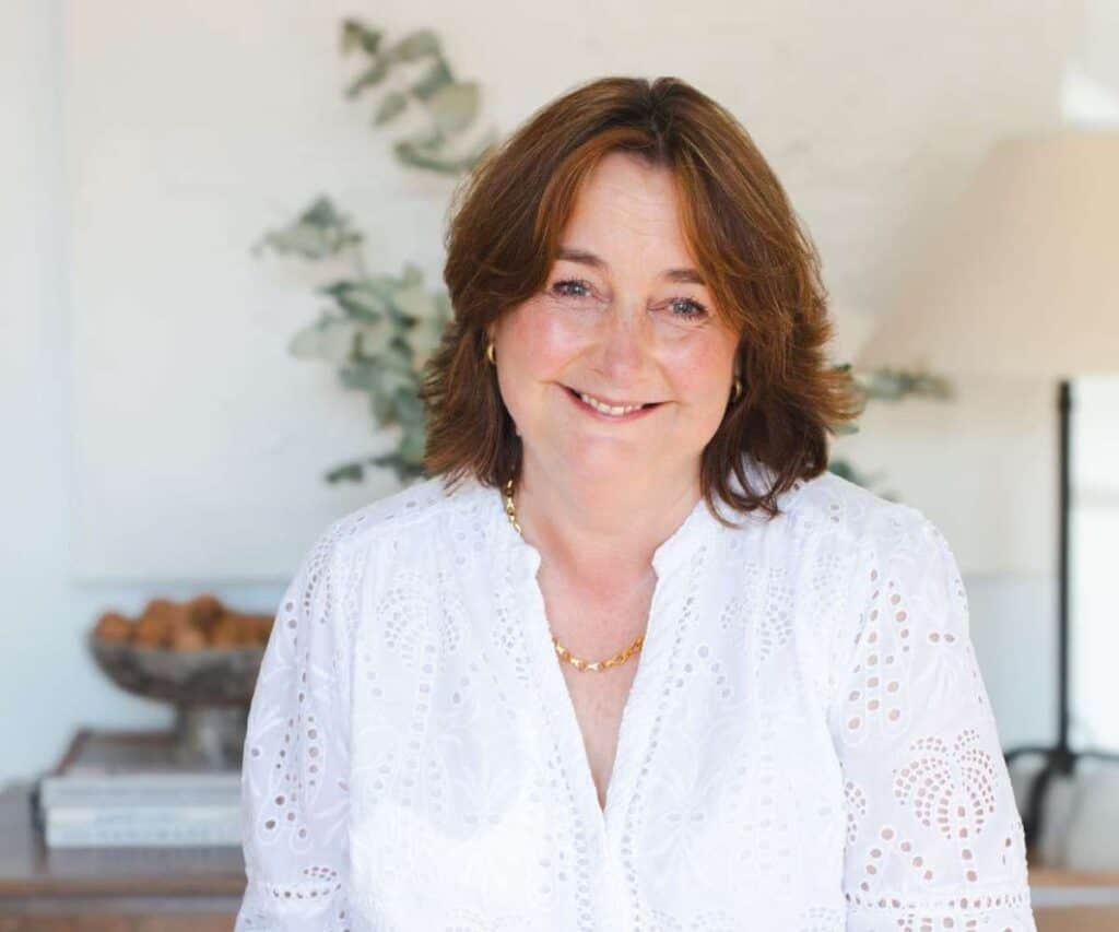 Smiling woman with shoulder-length brown hair in a bright, modern interior.