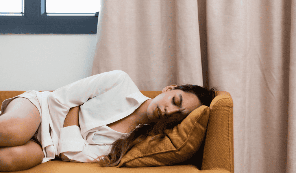 Woman resting peacefully on a couch in a cozy home setting.