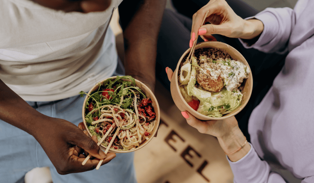 Two people enjoying nutritious salads and pasta bowls at Wild Muse Wellness.