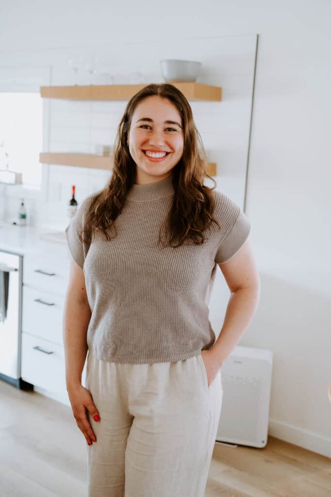 Smiling woman in a cozy kitchen, promoting wellness and happiness.