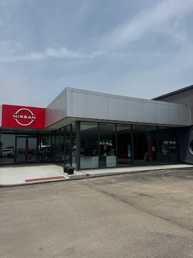 Modern Nissan dealership with glass facade, prominent red Nissan logo, paved entry—perfect for Willowood Ventures automotive marketing.