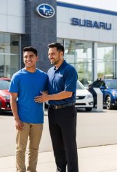Two men stand smiling outside a Subaru dealership, showcasing the Subaru brand and dealership location for Willowood Ventures’ automotive marketing. Multiple parked Subaru vehicles and the prominent Subaru logo highlight the dealership setting.