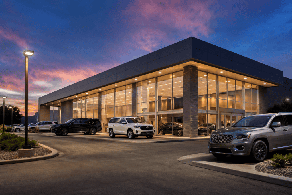 Modern car dealership showroom exterior at dusk with vehicles on display