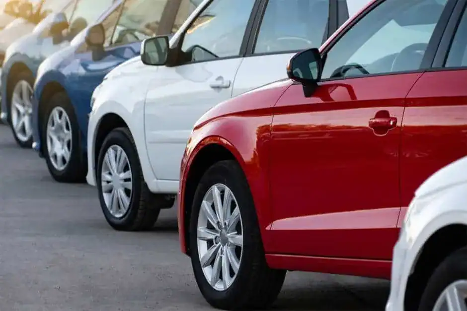 Red and white cars parked in a dealership lot for automotive marketing presentations, showcasing vehicle variety.