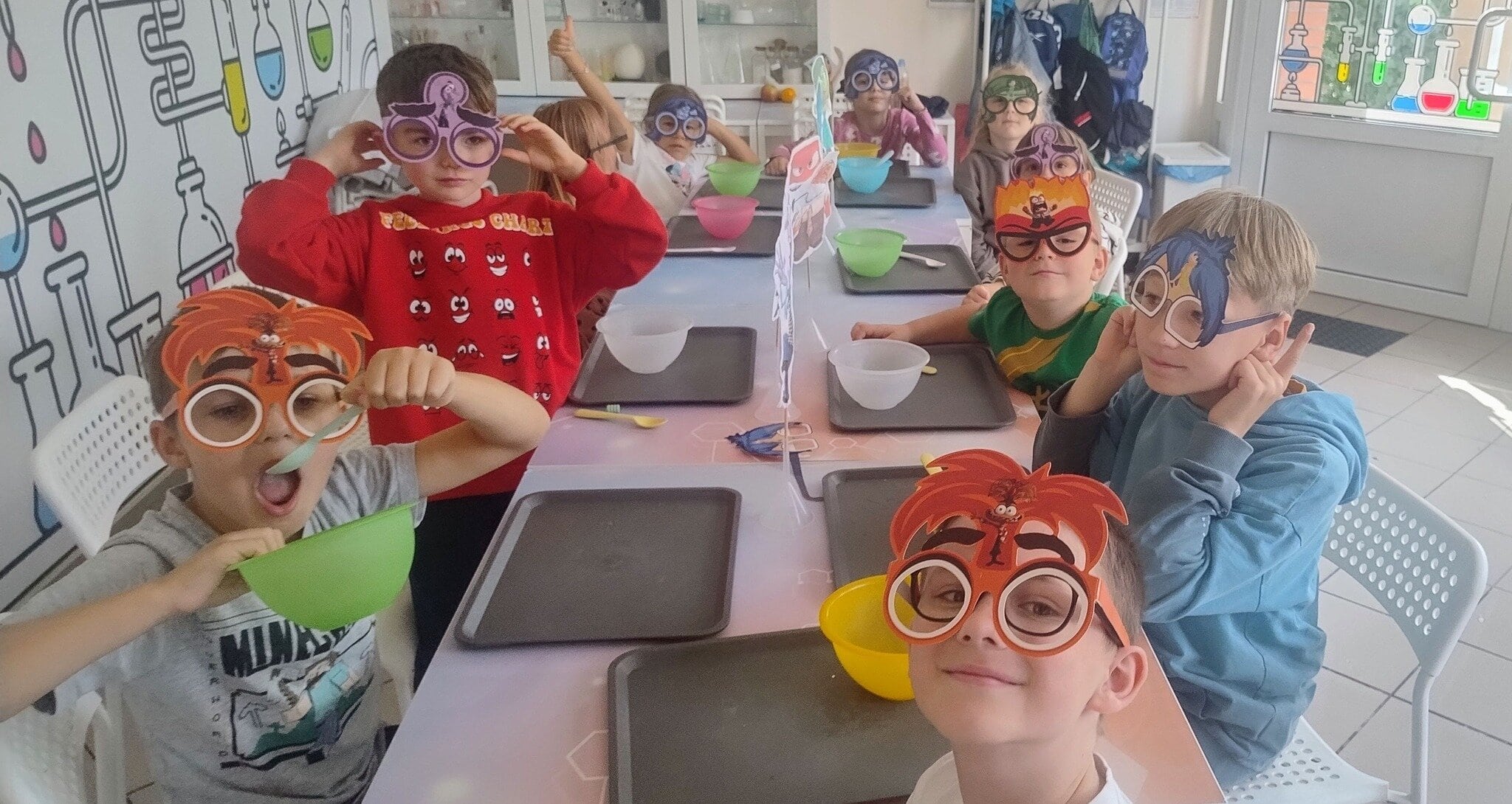 Kolorowa grupa dzieci w maskach naukowych na zajęciach eksperymentalnych w szkole, uczestniczących w warsztatach w laboratorium edukacyjnym Wittlab.