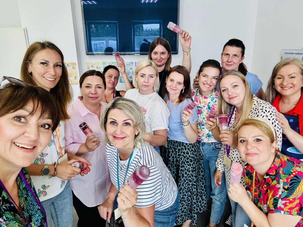 Szeroki kadr grupowy z uśmiechniętymi pracownikami Wittlab, trzymającymi lody, w nowoczesnym biurze, promujący atmosferę team buildingu i pozytywne relacje w zespole.