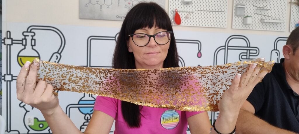 Kontrolka reakcji chemicznych, kobieta z okularami, eksperyment naukowy, przylaboratoryjna atmosfera, kreatywne badania chemiczne z cieczą, edukacja chemiczna, laboratoryjne eksperymenty, nauka dla dzieci i dorosłych, science show, wyzwania naukowe w laboratorium.