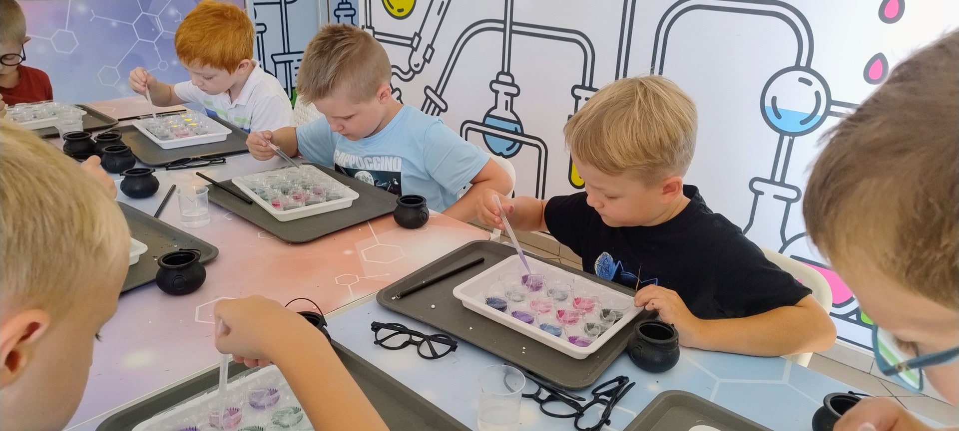 Kolorowe dzieci w pracowni naukowej, uczą się chemii i eksperymentują z kolorowymi roztworami w laboratoriach dla dzieci, edukacja przez zabawę w centrum nauki Wittlab.