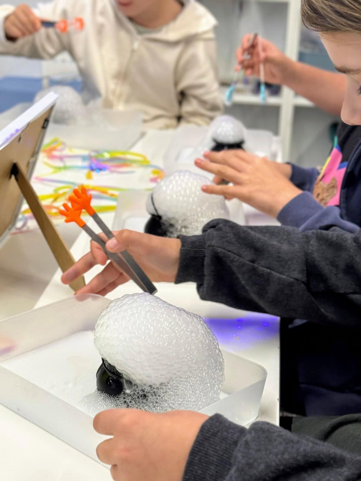 Inżynieria dźwięku, eksperymenty z wodą i bańkami mydlanymi w laboratorium szkolnym. Młodzi uczniowie uczą się tworzenia i manipulacji efektami akustycznymi i wizualnymi podczas zajęć edukacyjnych.