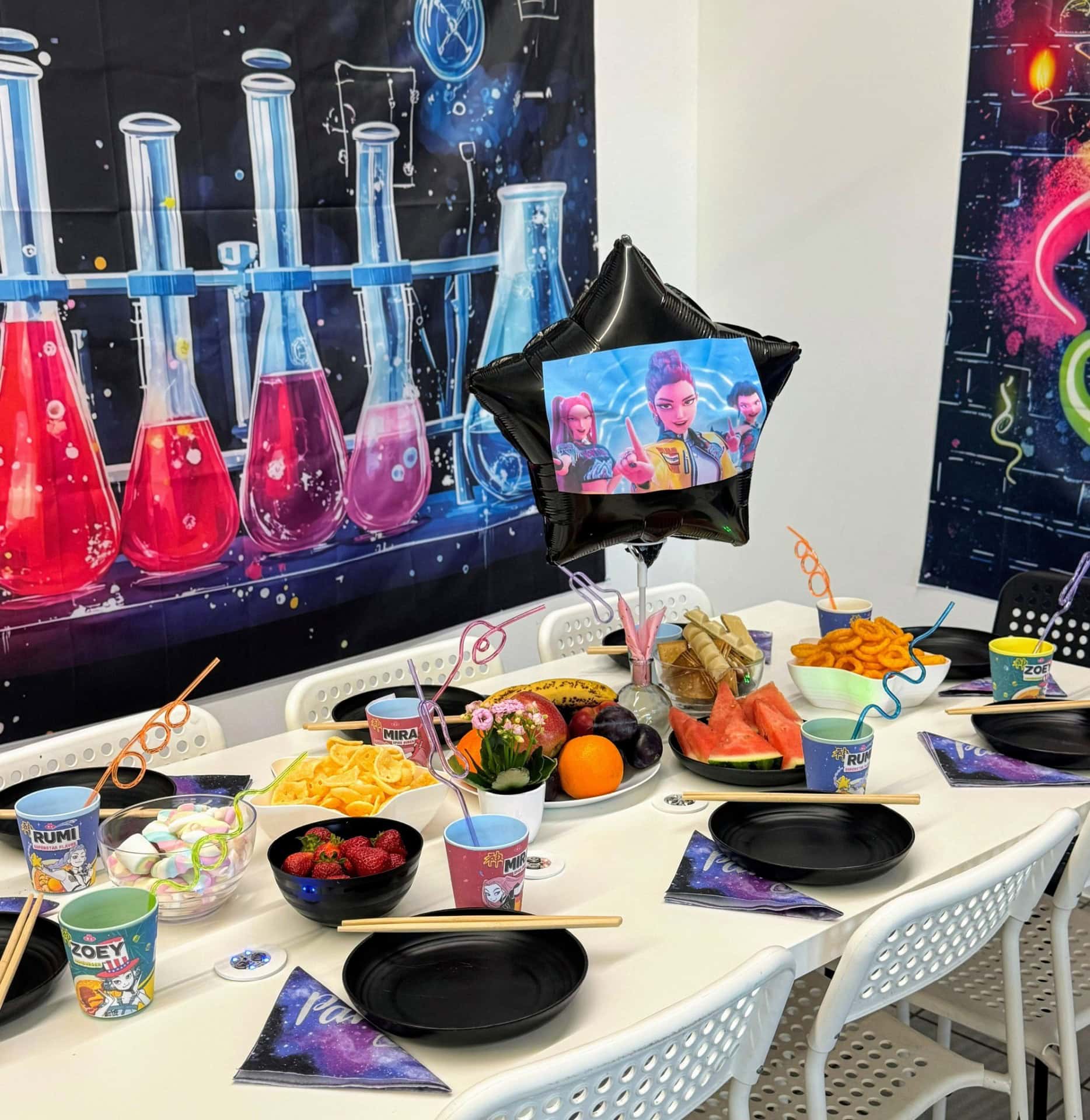 Kolorowe dekoracje i przekąski na urodzinowym stole w stylu "Wojowniczek Załogi", z balonami i kubkami z bohaterkami z filmu, idealne na imprezę dla dzieci.
