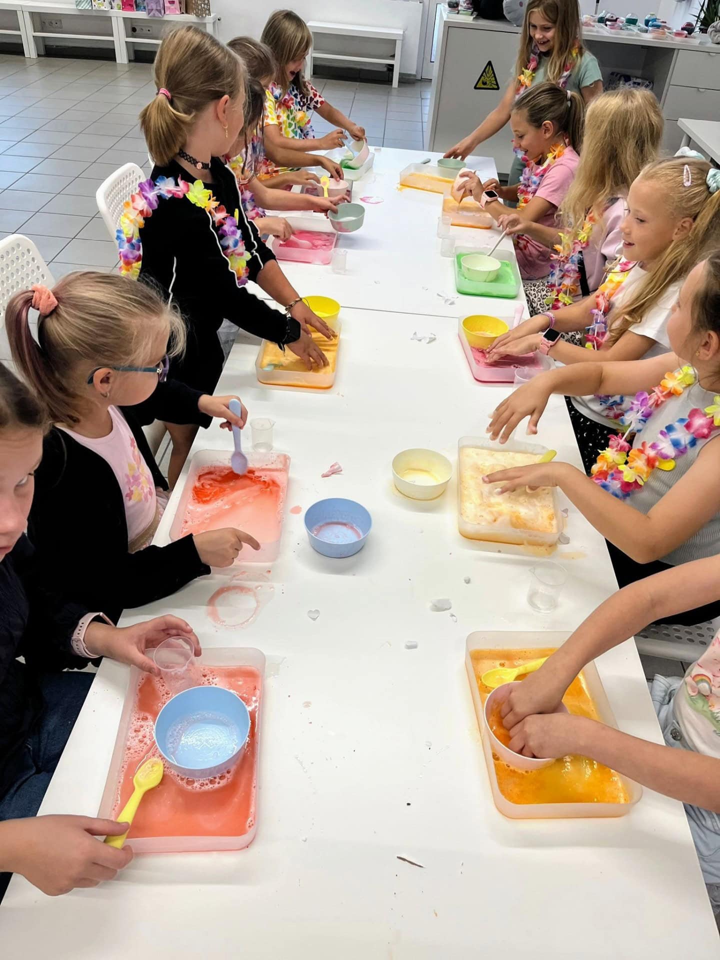 Kolorowe dzieci bawią się i tworzą w pracowni plastycznej, korzystając z farb, misek i pędzli, co zapewnia edukacyjne i kreatywne doświadczenia w przyjaznym środowisku.