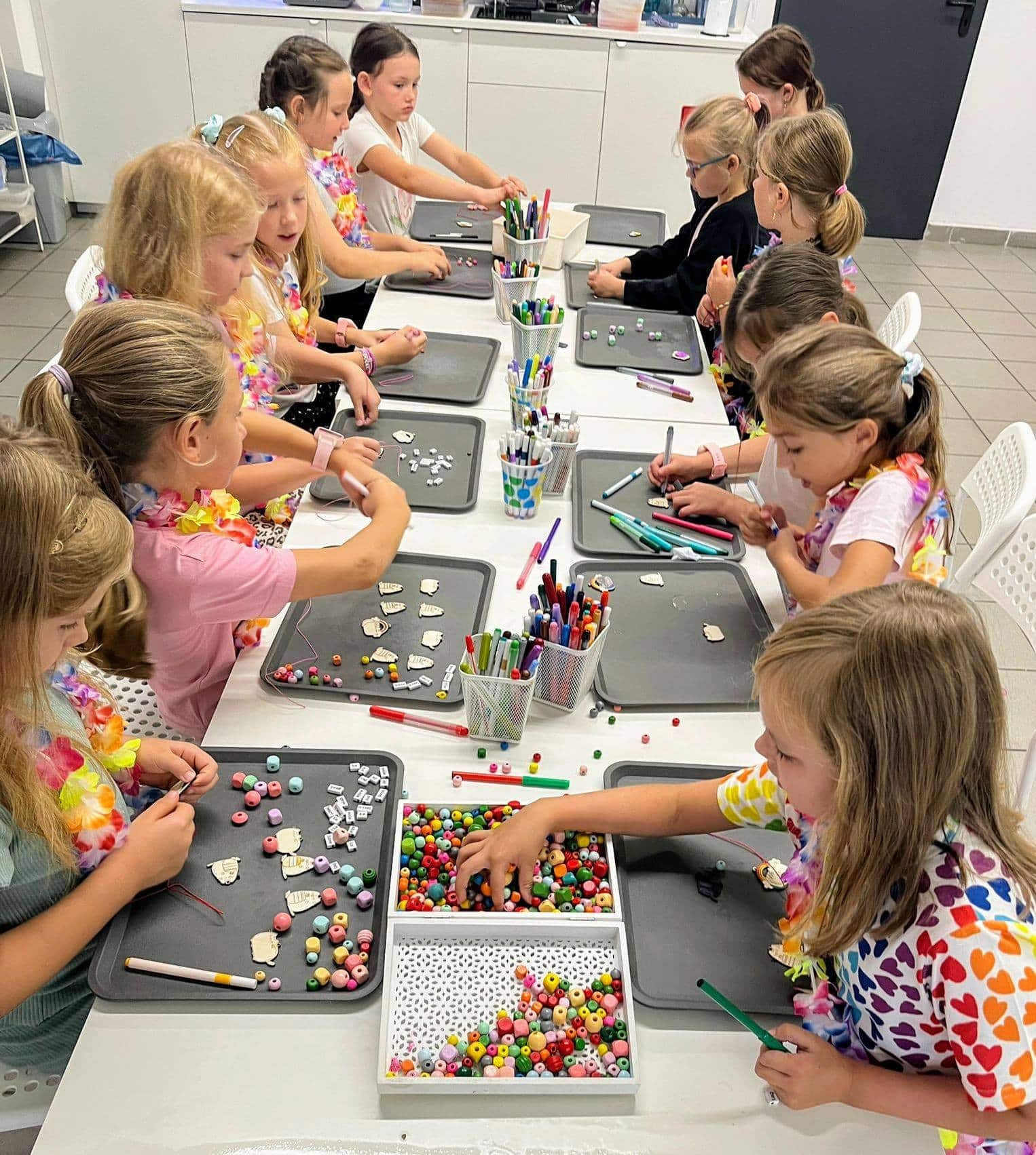 Kolorowe koraliki i zestawy do tworzenia biżuterii na warsztatach dla dzieci w kreatywnym centrum Wittlab. Młode uczestniczki uczą się projektowania unikalnych ozdób, rozwijając zdolności manualne i wyobraźnię.