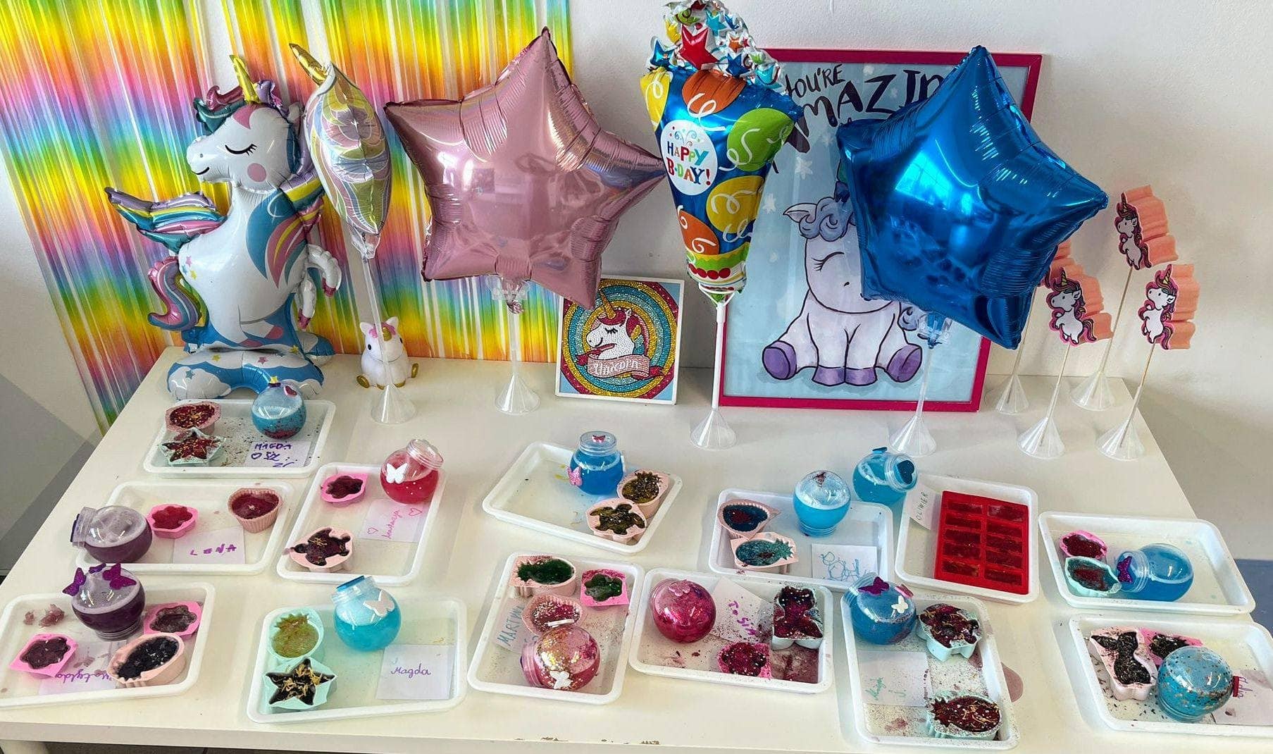 Kolorowe balony urodzinowe z motywem jednorożca, tła w pasy, personalizowane słodkości i dekoracje na imprezę dla dzieci z motywem jednorożca i tęczowych akcentów.