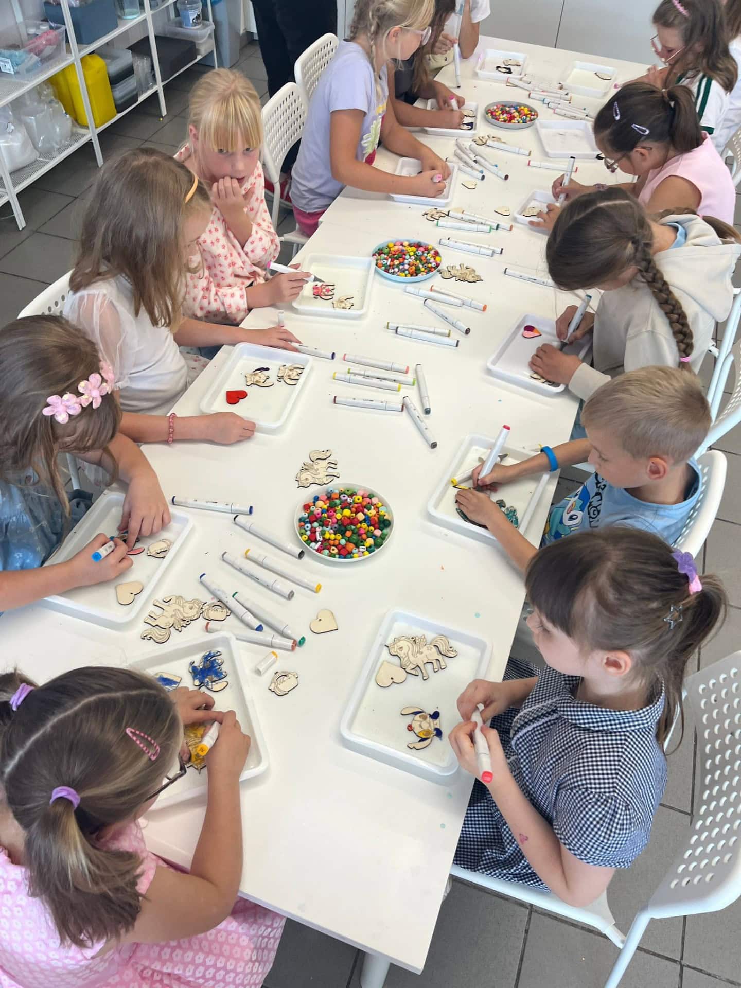 Kolorowe dzieci tworzą ręcznie dekoracje z drewna w warsztatach artystycznych dla dzieci, wykorzystując markery, naklejki i elementy do ozdabiania.