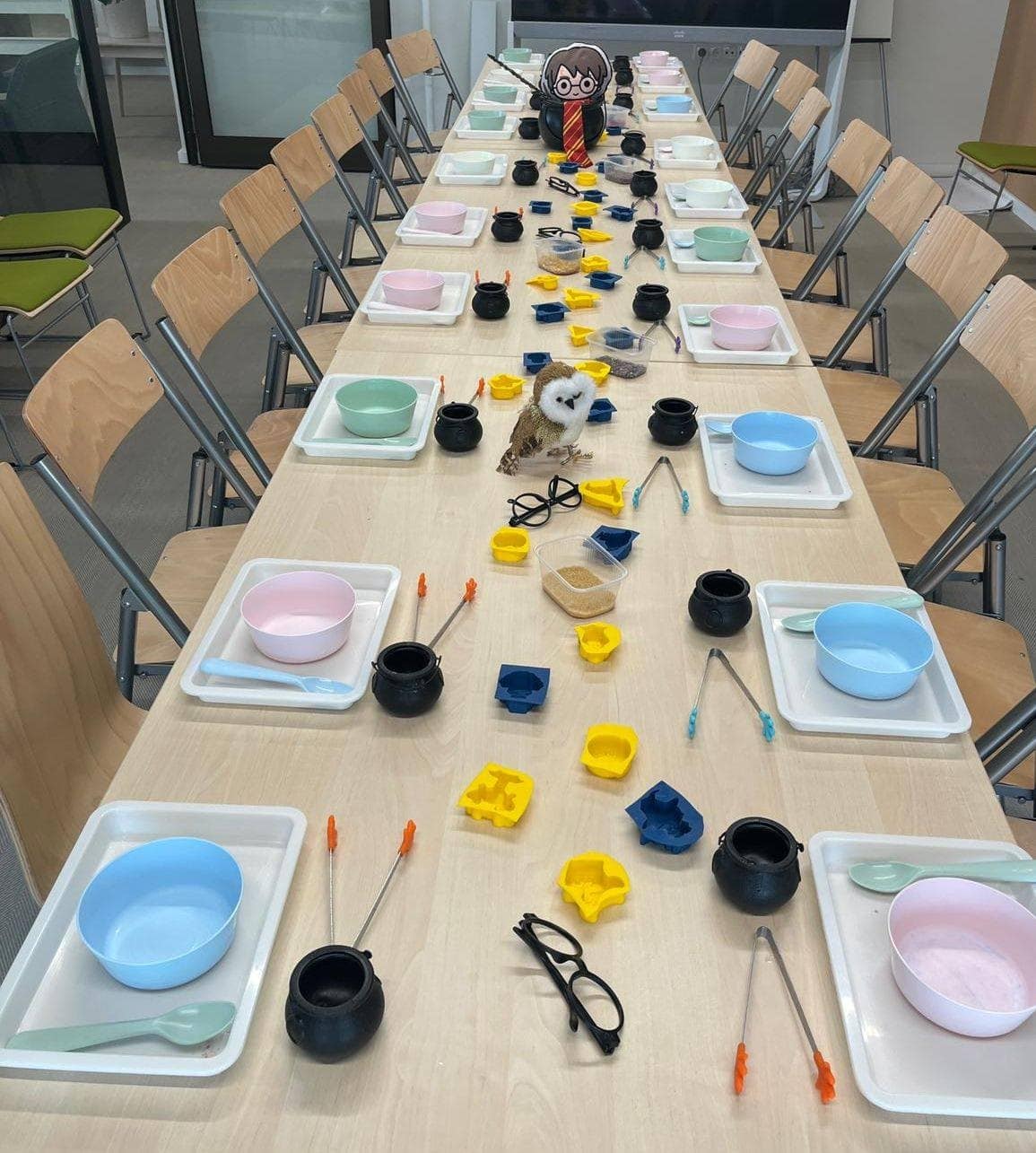 Kolorowa sala do zajęć edukacyjnych dla dzieci z różnorodnym wyposażeniem, zabawkami i materiałami do twórczej nauki. Wyposażona w stół, naczynia, figurki, śrubki i inne akcesoria edukacyjne, idealna do rozwijania umiejętności manualnych i kreatywności.