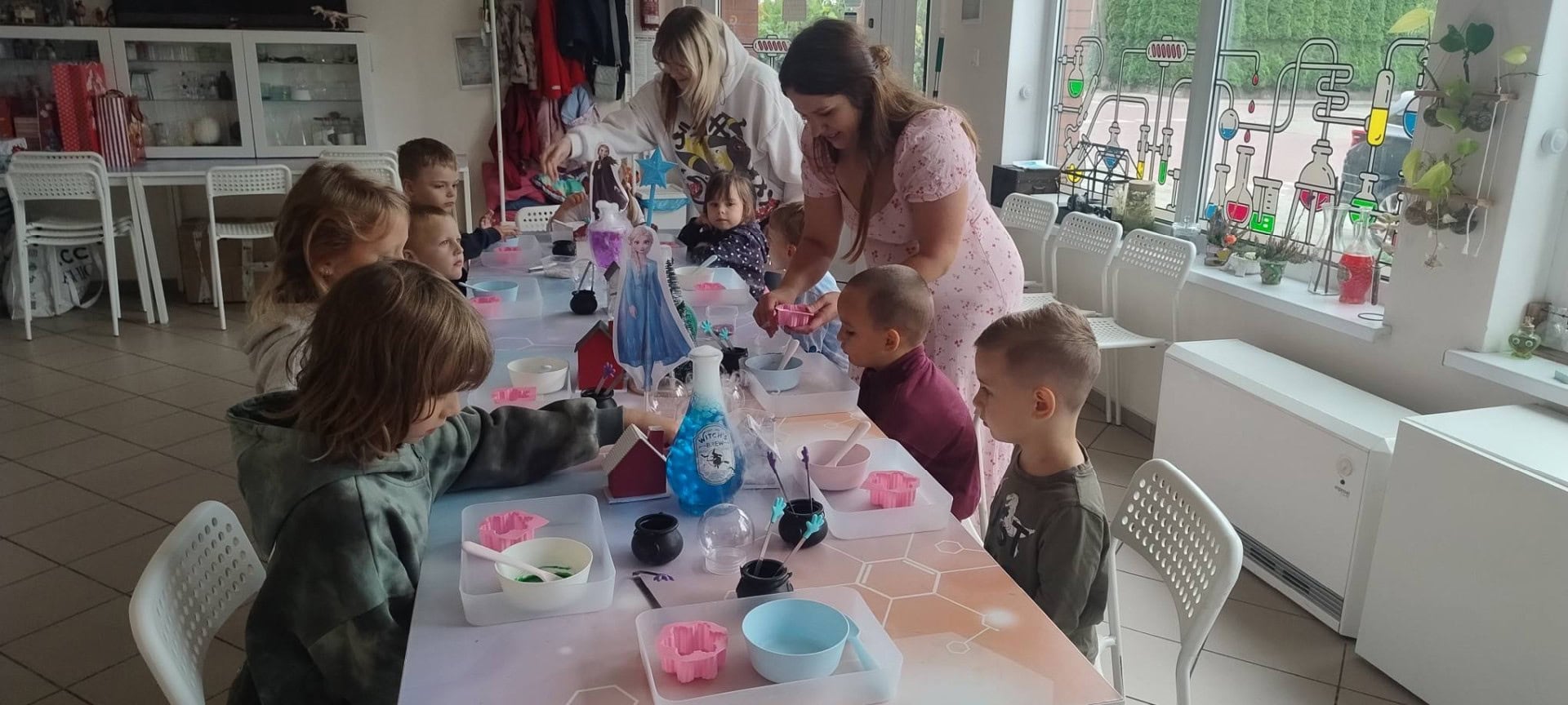 Kolorowa zabawa sensoryczna dla dzieci w nowoczesnym centrum edukacyjnym, z udziałem prowadzących i kreatywnymi narzędziami do rękodzieła w jasnym, przyjaznym wnętrzu.