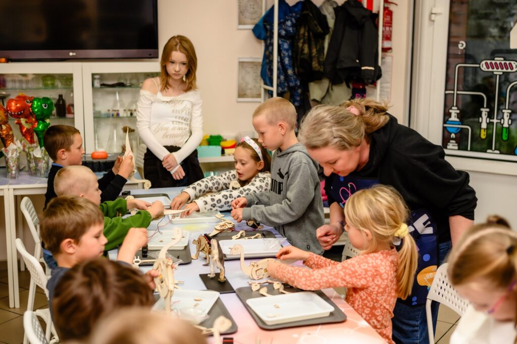 Tłumaczenie dzieci bawiące się drewnianymi robotami na warsztatach edukacyjnych w centrum kreatywnym w Polsce, nauka i zabawa dla najmłodszych, edukacyjne zajęcia dla dzieci, rozwijanie zdolności manualnych, kreatywne spędzanie czasu.