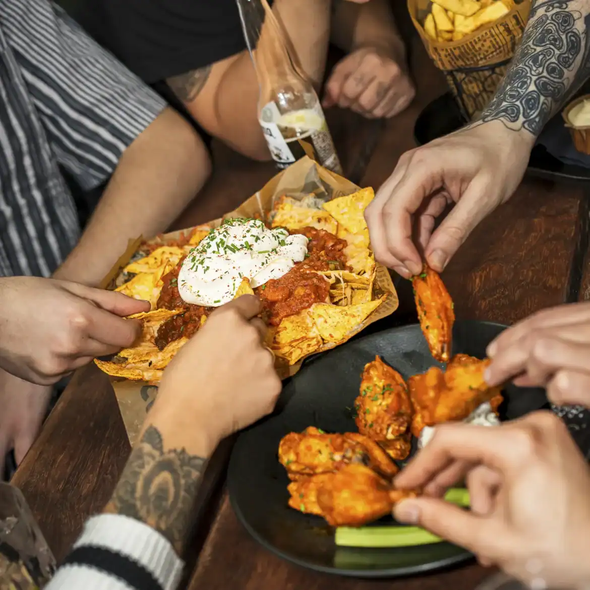 People sharing spicy chicken wings and nachos at Belushi's during the World Cup.