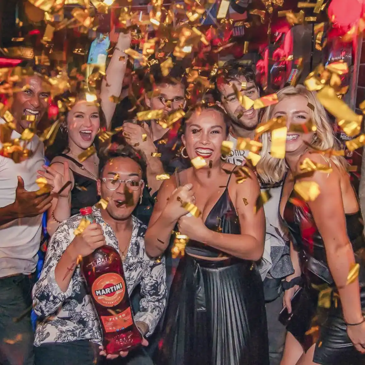 Group of friends celebrating at Belushi's during the World Cup with confetti and drinks.
