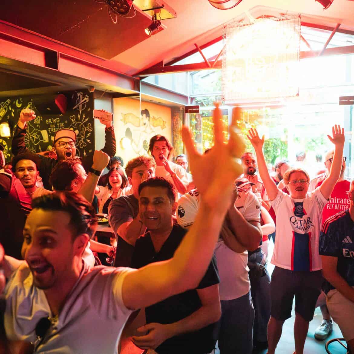 Crowd celebrating at Belushi's during the World Cup event in a lively bar.