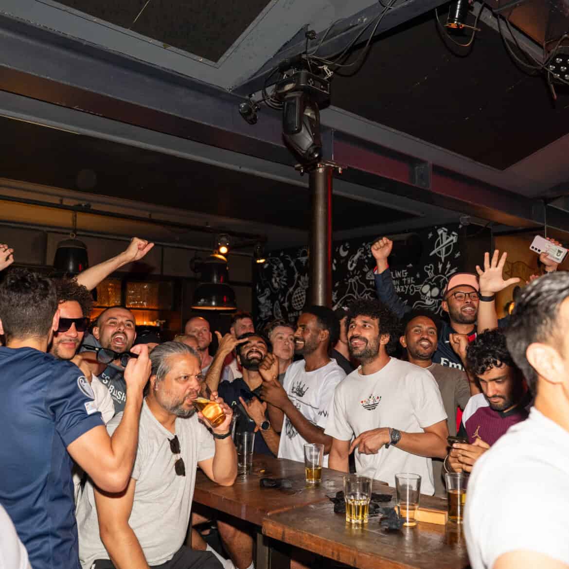 Crowd enjoying football match at Belushi's during World Cup event.