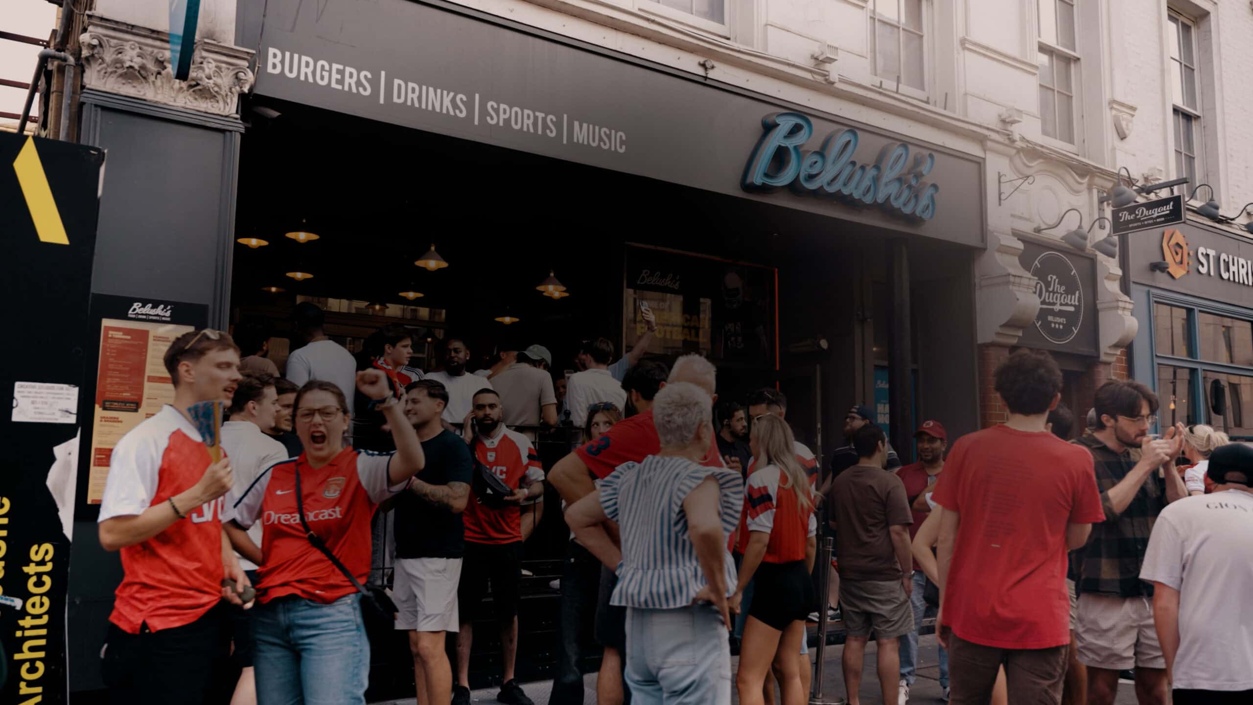 Crowd of people outside Belushi's pub during a sports event or World Cup.