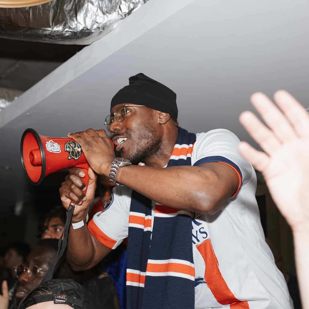 Man with megaphone at Belushi's during World Cup event.