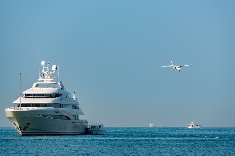A luxury yacht and seaplane under a clear blue sky, capturing travel and leisure in the open sea.