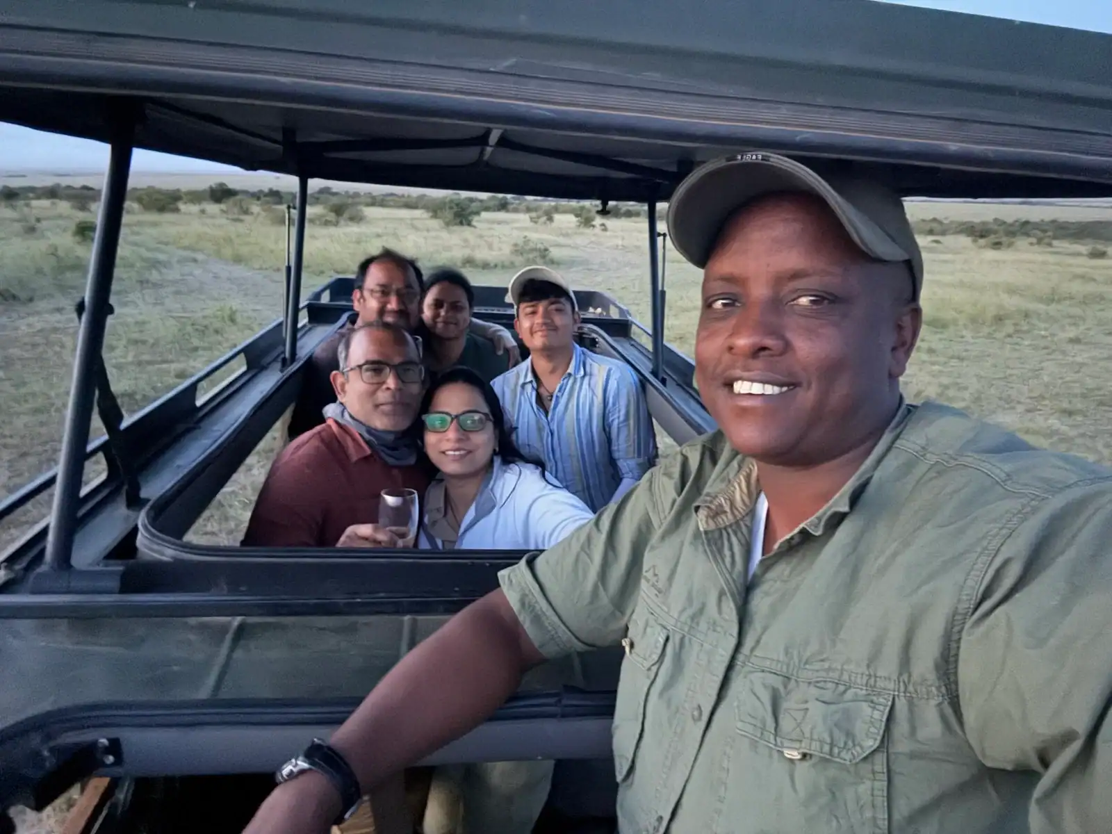 Masai Mara Safari June 2026 with a group of tourists on an open-air vehicle in the Masai Mara wilderness.