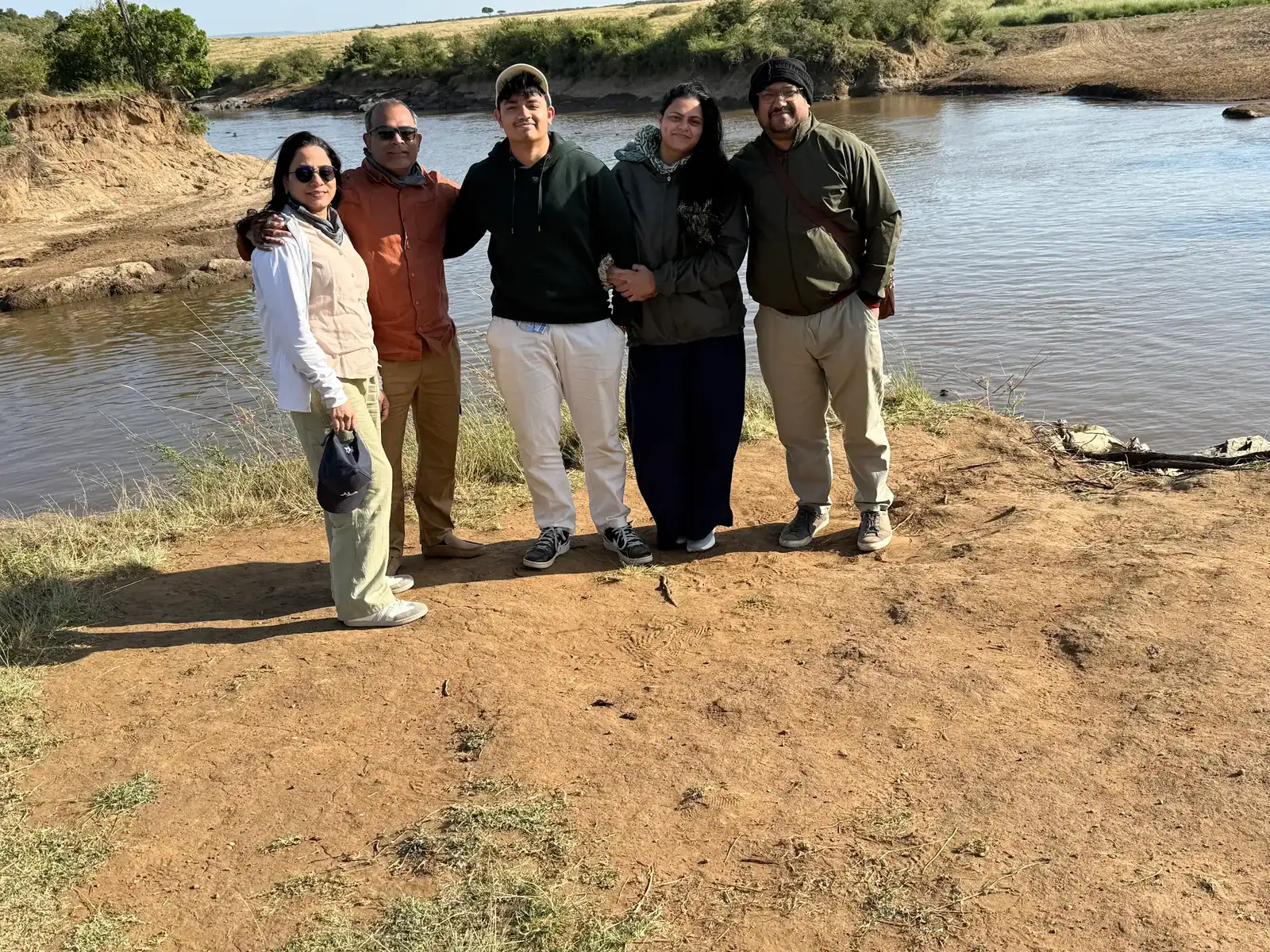 Group of five people enjoying nature by a river in outdoor adventure setting.