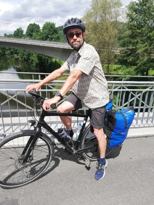 Mann mit Fahrrad und Helm auf Brücke bei 2Rad Center Werl.