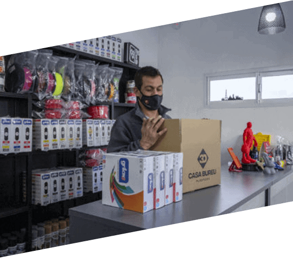 Búsqueda de productos en 3D Casa Bureu Plásticos, tienda especializada en plásticos y artículos de policarbonato para proyectos. El empleado revisa una caja con productos en un ambiente de tienda.