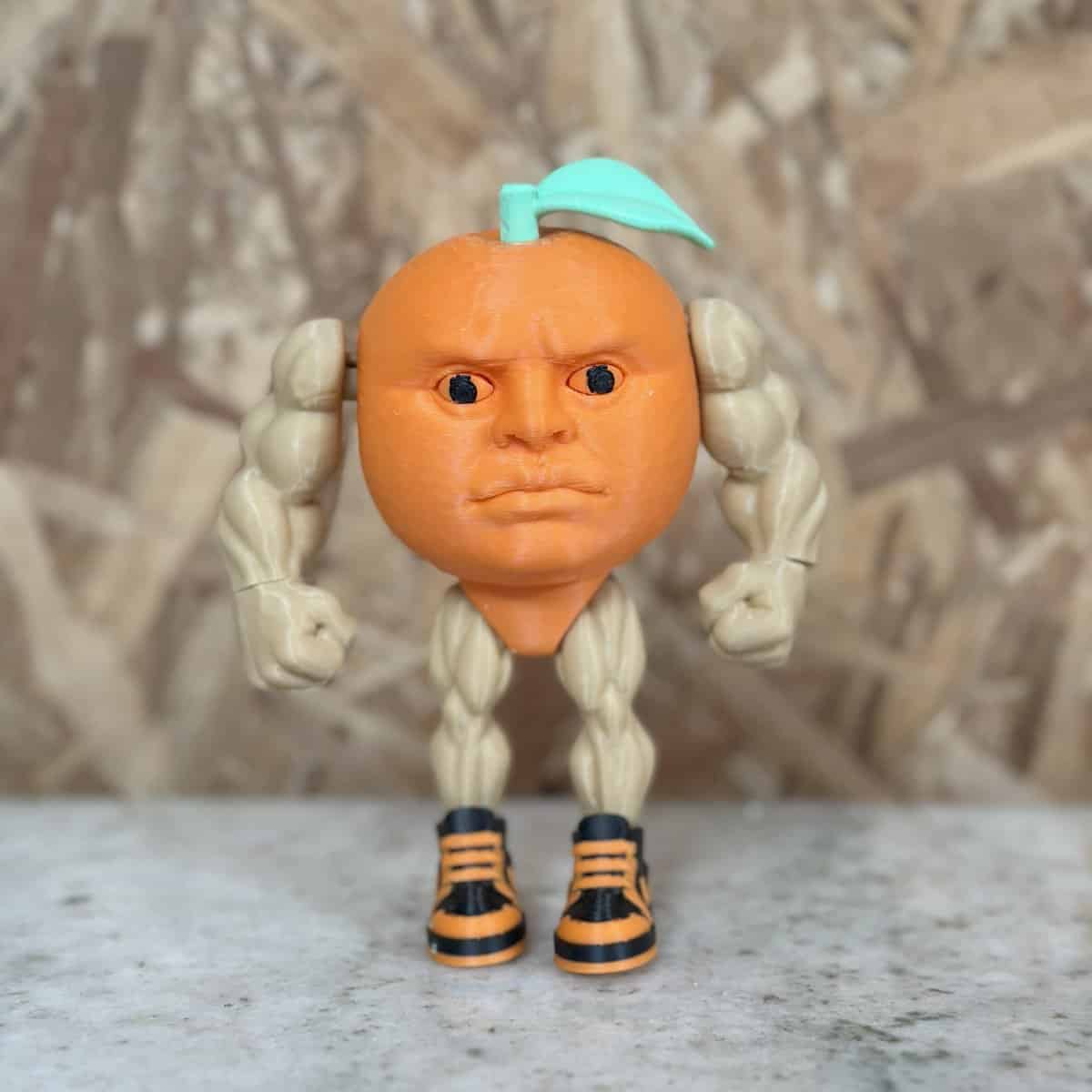 Miniatura de juguete con rostro humano, cuerpo de cáscara de naranja y piernas con zapatillas deportivas, representando creatividad en plásticos 3D Casa Bureu.